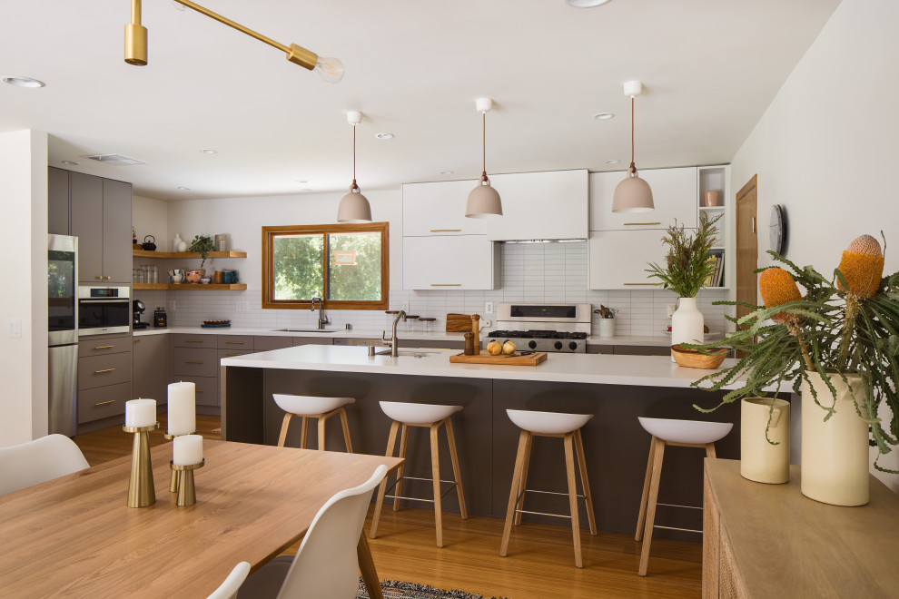 Expansive scandinavian galley eat-in kitchen in Los Angeles with an undermount sink, flat-panel cabinets, grey cabinets, quartz benchtops, white splashback, subway tile splashback, stainless steel appliances, bamboo floors, a peninsula, yellow floor and white benchtop.