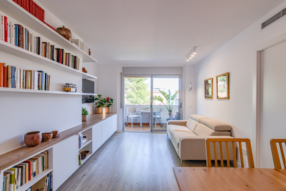 Bild på ett mellanstort minimalistiskt allrum med öppen planlösning, med ett bibliotek, vita väggar, mellanmörkt trägolv, en väggmonterad TV och beiget golv