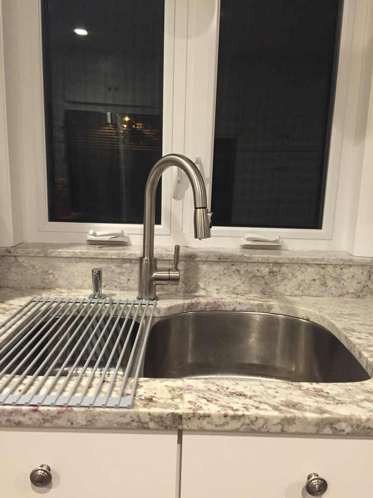 Example of a mid-sized transitional l-shaped medium tone wood floor enclosed kitchen design in Providence with an undermount sink, shaker cabinets, white cabinets, marble countertops, stainless steel appliances and a peninsula