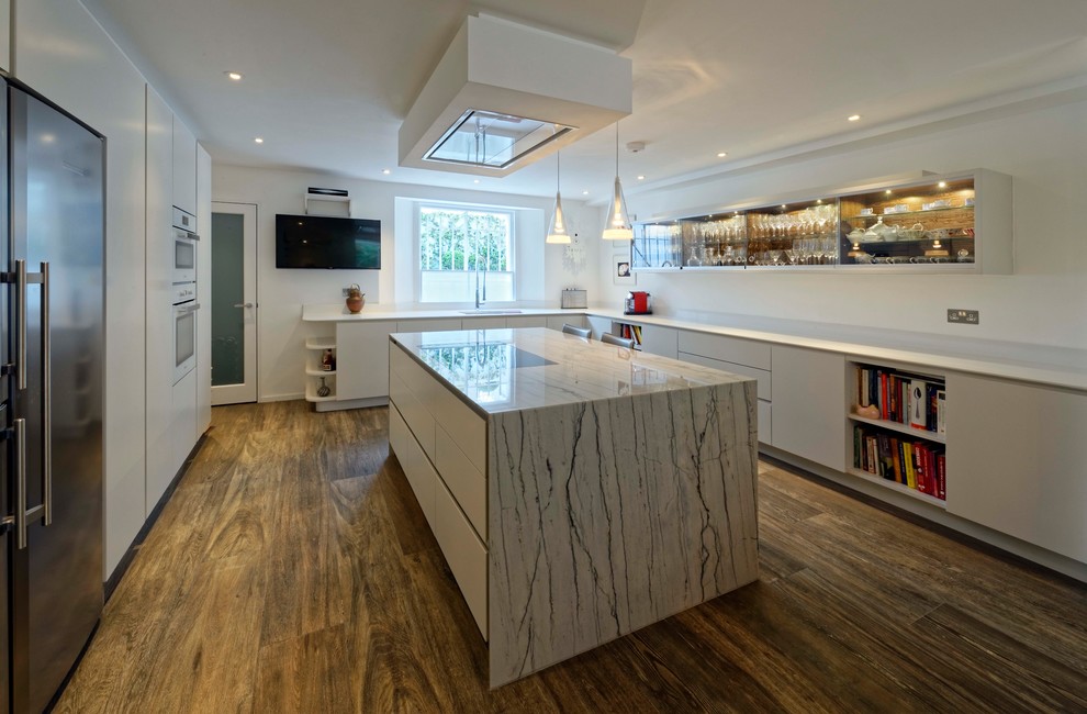 This is an example of a mid-sized contemporary l-shaped open plan kitchen in London with flat-panel cabinets, white cabinets, marble benchtops, ceramic floors, with island, brown floor and white benchtop.