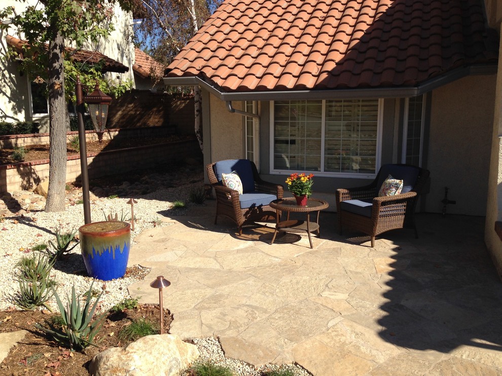 Mid-sized mediterranean front yard patio in Los Angeles with a water feature and natural stone pavers.