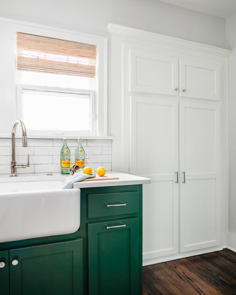 Inspiration for a mid-sized transitional medium tone wood floor and brown floor kitchen remodel in Chicago with a farmhouse sink, shaker cabinets, green cabinets, quartz countertops, white backsplash, subway tile backsplash, stainless steel appliances, an island and white countertops