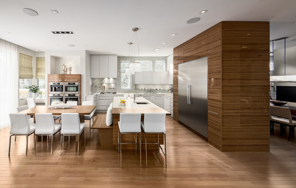 Photo of a contemporary l-shaped eat-in kitchen in Ottawa with flat-panel cabinets, dark wood cabinets, grey splashback, stainless steel appliances, medium hardwood floors and with island.