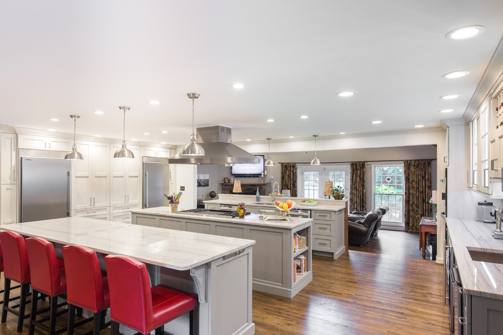 Large transitional single-wall medium tone wood floor and brown floor eat-in kitchen photo with an undermount sink, shaker cabinets, stainless steel appliances, two islands, white cabinets, marble countertops, multicolored backsplash and matchstick tile backsplash