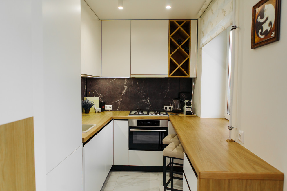 This is an example of a mid-sized scandinavian u-shaped open plan kitchen in Saint Petersburg with an undermount sink, flat-panel cabinets, white cabinets, wood benchtops, black splashback, window splashback, panelled appliances, ceramic floors, no island, white floor and yellow benchtop.
