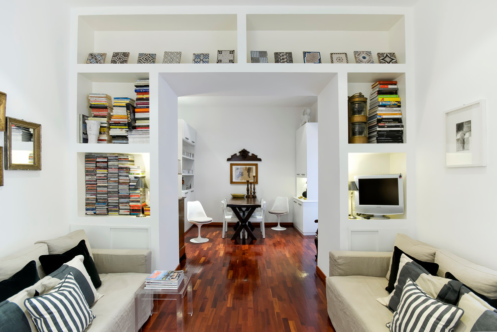 This is an example of a modern living room in Rome with white walls, medium hardwood floors and a freestanding tv.