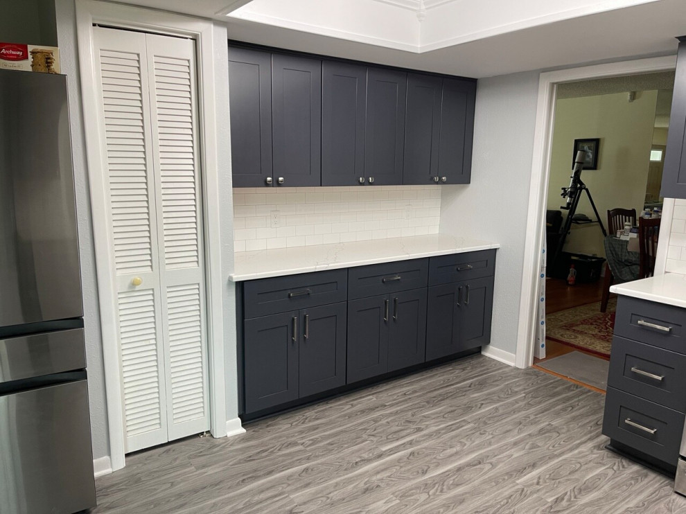 Example of a mid-sized transitional l-shaped kitchen pantry design in Tampa with shaker cabinets, black cabinets, quartz countertops, white backsplash and subway tile backsplash