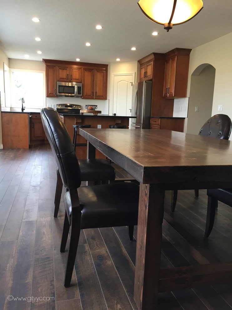 Mid-sized mountain style l-shaped laminate floor and black floor eat-in kitchen photo in Calgary with a drop-in sink, raised-panel cabinets, medium tone wood cabinets, quartzite countertops, white backsplash, ceramic backsplash, stainless steel appliances and an island
