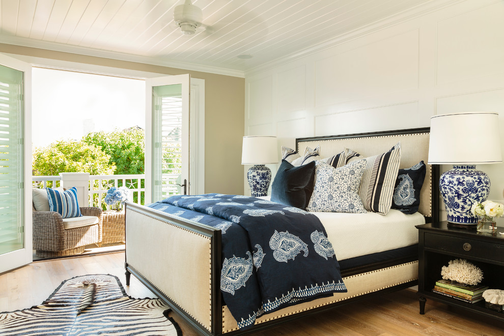 This is an example of a large beach style master bedroom in Orange County with grey walls and light hardwood floors.
