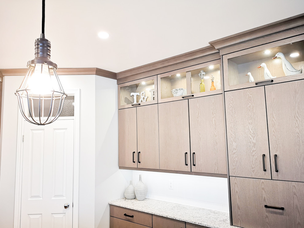 Large transitional u-shaped light wood floor and brown floor eat-in kitchen photo with an undermount sink, flat-panel cabinets, beige cabinets, quartz countertops, white backsplash, subway tile backsplash, stainless steel appliances, an island and white countertops