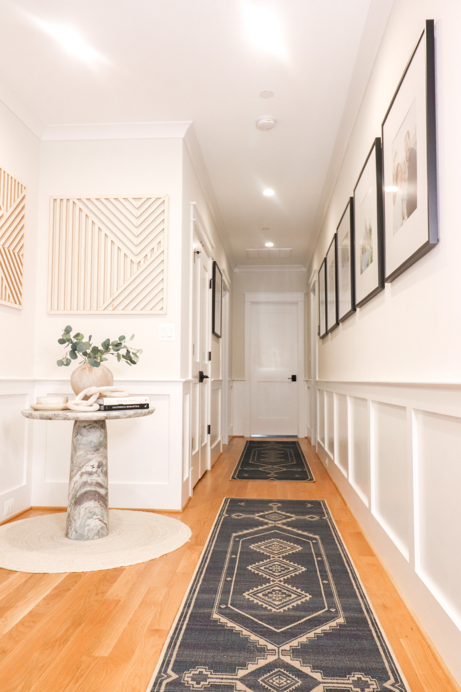 Hallways to bedrooms designed with a gallery wall, accent table, runners
