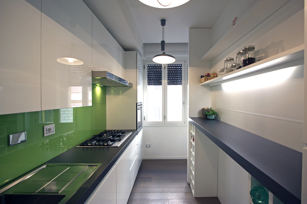 Small contemporary galley eat-in kitchen in Rome with a drop-in sink, flat-panel cabinets, white cabinets, quartz benchtops, green splashback, glass sheet splashback, stainless steel appliances, medium hardwood floors and with island.