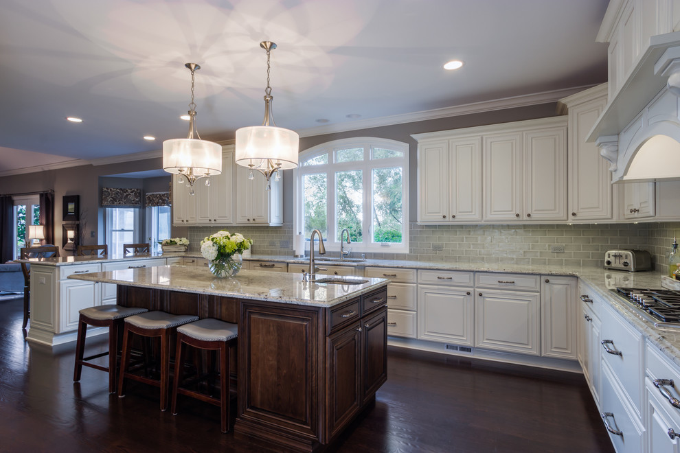 Kitchen - large transitional u-shaped dark wood floor kitchen idea in Chicago with a double-bowl sink, raised-panel cabinets, white cabinets, granite countertops, gray backsplash, subway tile backsplash, stainless steel appliances and an island