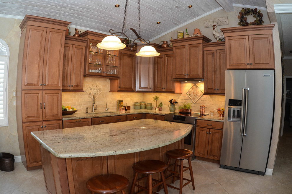 Open concept kitchen - mid-sized rustic l-shaped travertine floor open concept kitchen idea in Tampa with an undermount sink, raised-panel cabinets, dark wood cabinets, limestone countertops, beige backsplash, stone tile backsplash, stainless steel appliances and an island