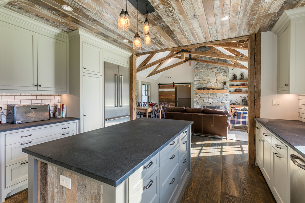 Inspiration for a large farmhouse u-shaped dark wood floor eat-in kitchen remodel in Boston with a farmhouse sink, recessed-panel cabinets, soapstone countertops, white backsplash, stainless steel appliances, an island, beige cabinets and subway tile backsplash