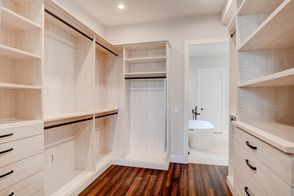 This is an example of a large transitional gender-neutral walk-in wardrobe in Dallas with flat-panel cabinets, light wood cabinets, laminate floors and brown floor.
