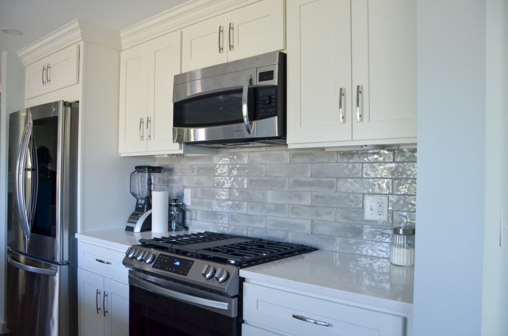 Retro Wohnküche mit weißen Schränken, Granit-Arbeitsplatte, Küchenrückwand in Grau, Rückwand aus Keramikfliesen, Küchengeräten aus Edelstahl, Vinylboden, Kücheninsel, braunem Boden und weißer Arbeitsplatte in Boston