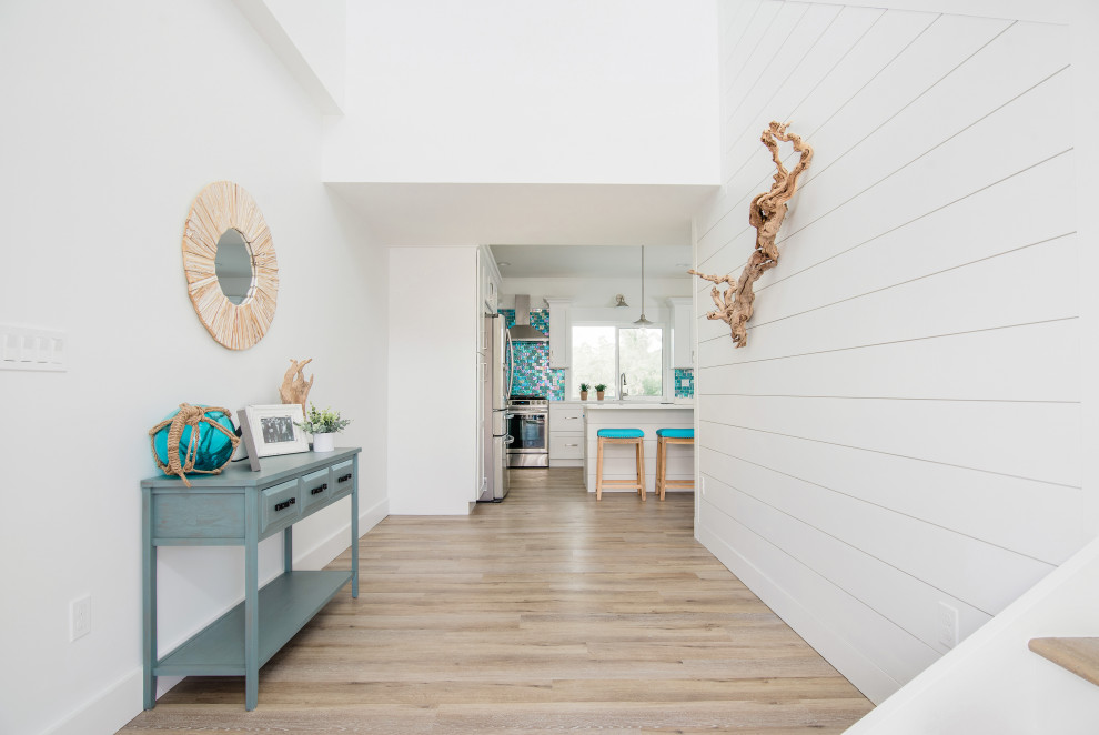 Photo of a mid-sized beach style foyer in Other with white walls, vinyl floors, a single front door, a gray front door and grey floor.