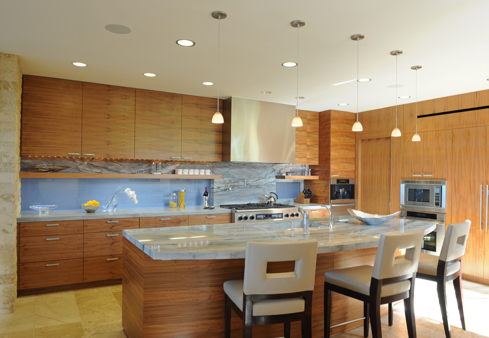 Photo of a large contemporary l-shaped open plan kitchen in Los Angeles with flat-panel cabinets, grey splashback, stone slab splashback, stainless steel appliances, an integrated sink, medium wood cabinets, granite benchtops, limestone floors and with island.