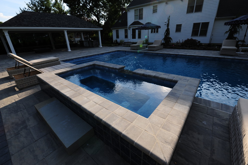 Design ideas for a large traditional backyard rectangular lap pool in Philadelphia with a hot tub and natural stone pavers.