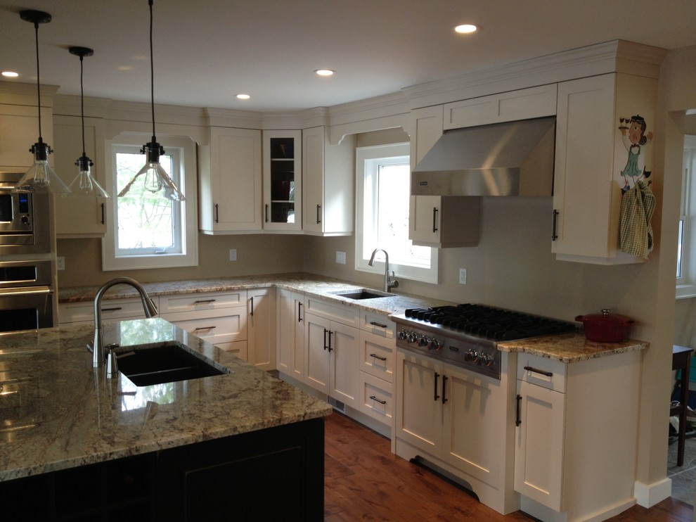 Inspiration for a mid-sized transitional l-shaped medium tone wood floor eat-in kitchen remodel in Toronto with a double-bowl sink, shaker cabinets, white cabinets, stainless steel appliances, an island and granite countertops