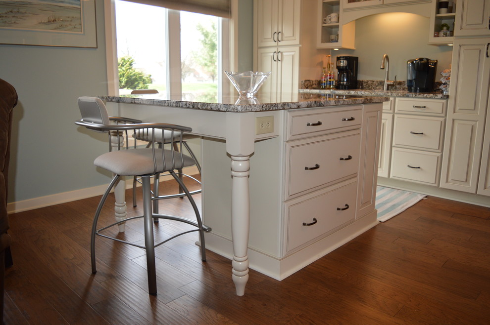 This is an example of a large traditional l-shaped eat-in kitchen in Other with an undermount sink, raised-panel cabinets, white cabinets, granite benchtops, stainless steel appliances, medium hardwood floors and multiple islands.