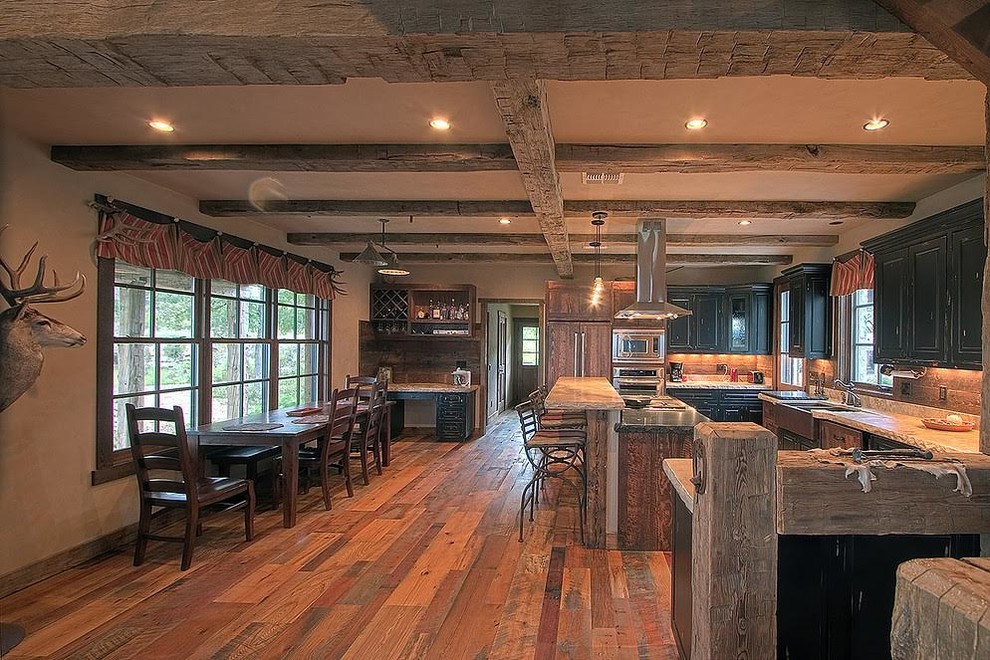 Photo of a mid-sized country u-shaped eat-in kitchen in Austin with a farmhouse sink, raised-panel cabinets, black cabinets, quartz benchtops, stainless steel appliances, medium hardwood floors, with island and brown floor.