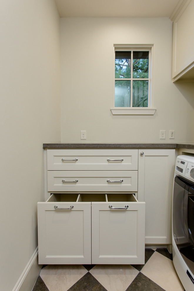 Design ideas for a mid-sized transitional l-shaped utility room in Houston with an undermount sink, recessed-panel cabinets, beige cabinets, limestone benchtops, beige walls, limestone floors and a side-by-side washer and dryer.