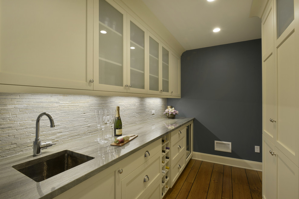 Design ideas for a mid-sized transitional galley wet bar in New York with an undermount sink, beaded inset cabinets, beige cabinets, quartzite benchtops, grey splashback, stone tile splashback, medium hardwood floors and brown floor.