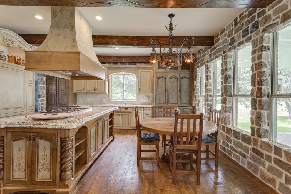 Photo of a mid-sized traditional l-shaped eat-in kitchen in Dallas with an undermount sink, raised-panel cabinets, distressed cabinets, granite benchtops, white splashback, travertine splashback, stainless steel appliances, medium hardwood floors, with island and brown floor.