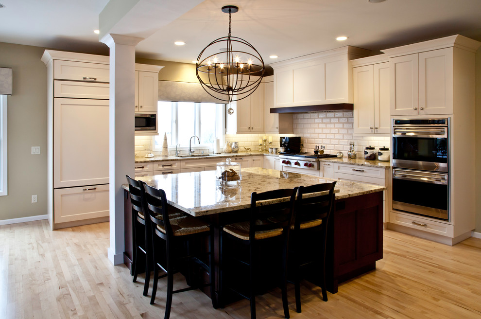 Inspiration for a large transitional l-shaped light wood floor and brown floor open concept kitchen remodel with an undermount sink, shaker cabinets, white cabinets, granite countertops, white backsplash, subway tile backsplash, paneled appliances and an island