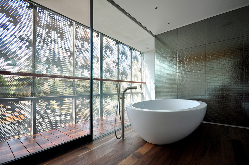 Design ideas for a contemporary bathroom in London with a freestanding tub and dark hardwood floors.