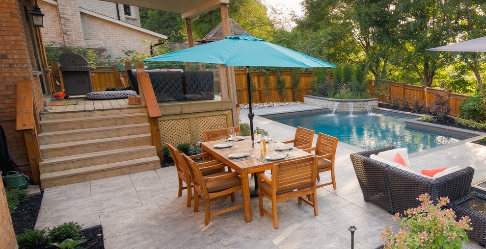 This is an example of a small contemporary backyard rectangular pool in Toronto with a hot tub and stamped concrete.