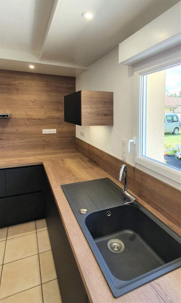 Design ideas for a large modern galley open plan kitchen in Other with terracotta flooring, beige floors, a drop ceiling, a submerged sink, flat-panel cabinets, black cabinets, laminate countertops, brown splashback, wood splashback, integrated appliances, an island and brown worktops.