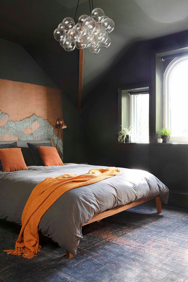 На фото: большая гостевая спальня (комната для гостей) в стиле фьюжн с черными стенами, деревянным полом, стандартным камином, фасадом камина из металла и черным полом с