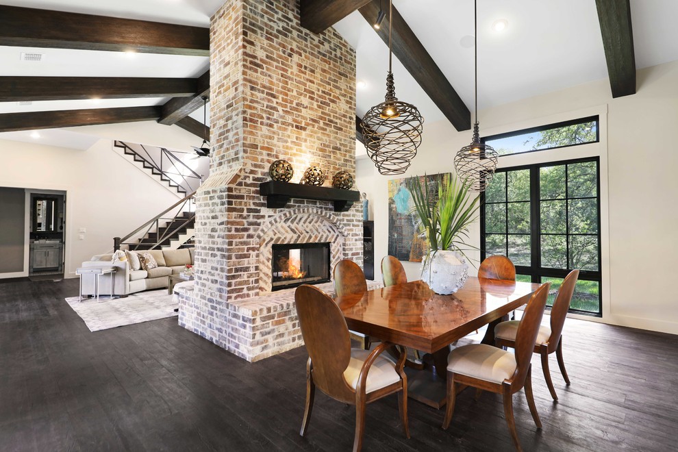 Transitional open plan dining in Austin with beige walls, dark hardwood floors, a two-sided fireplace, a brick fireplace surround and black floor.