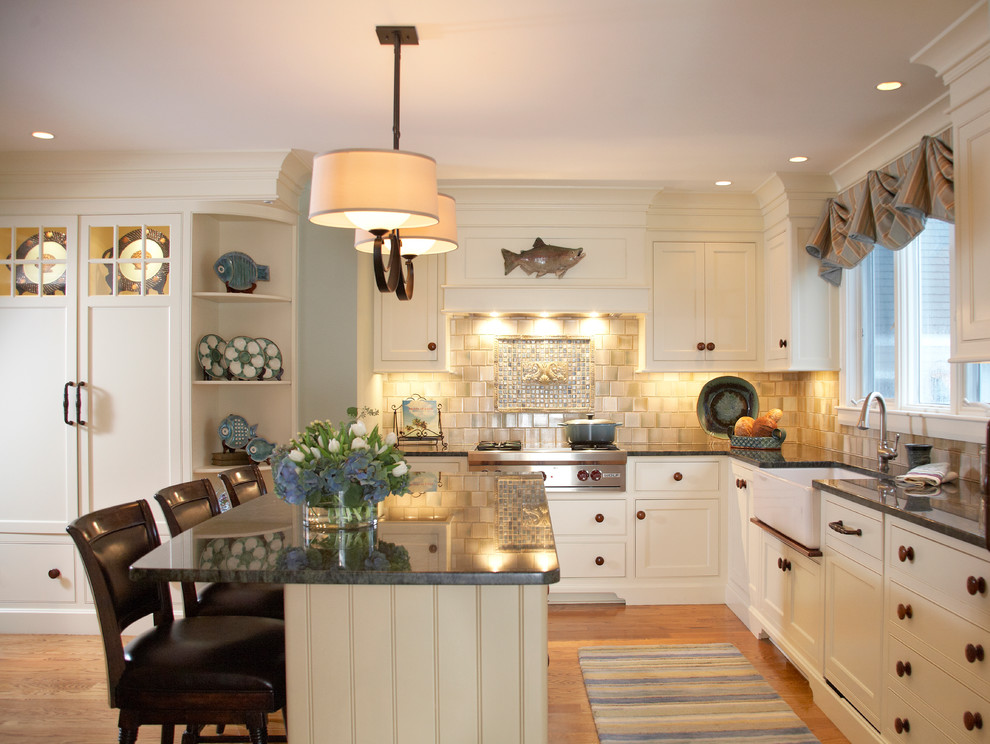 Design ideas for a beach style l-shaped kitchen in Boston with a farmhouse sink, shaker cabinets, white cabinets, granite benchtops and beige splashback.