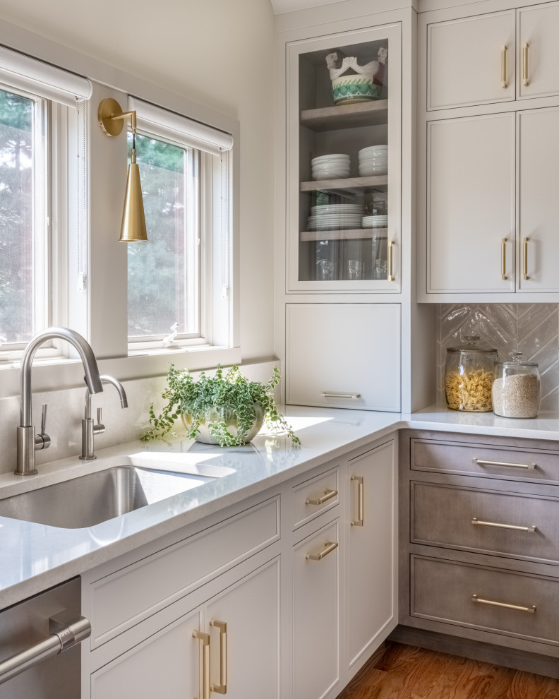 Inspiration for a mid-sized transitional l-shaped eat-in kitchen in Philadelphia with an undermount sink, flat-panel cabinets, beige cabinets, quartz benchtops, beige splashback, ceramic splashback, stainless steel appliances, dark hardwood floors, with island, brown floor and white benchtop.