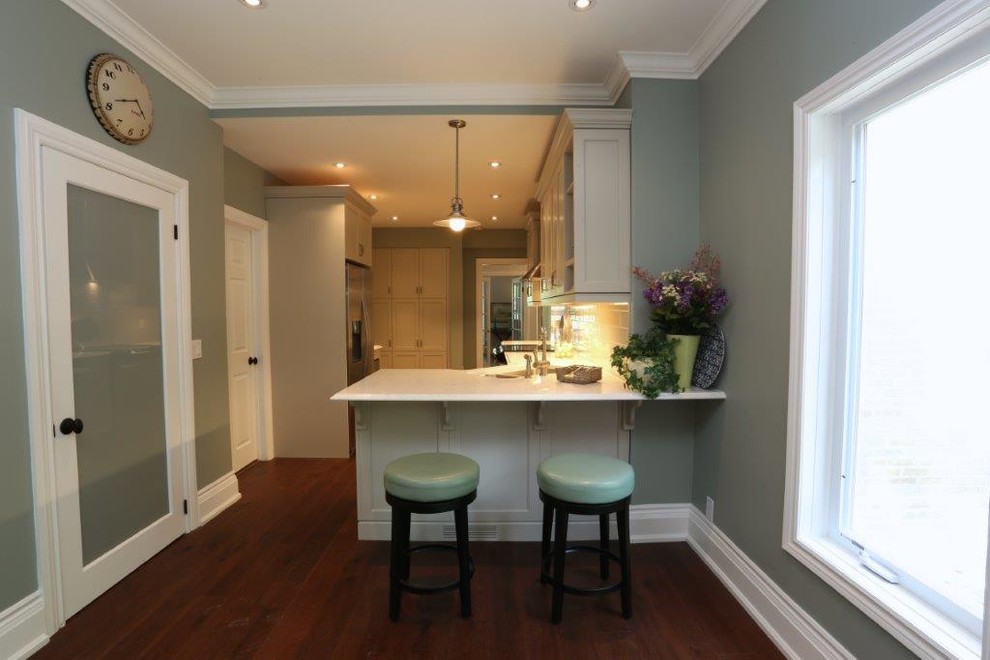 Inspiration for a mid-sized transitional single-wall medium tone wood floor and brown floor enclosed kitchen remodel in Toronto with a double-bowl sink, shaker cabinets, white cabinets, quartz countertops, white backsplash, subway tile backsplash, stainless steel appliances and a peninsula
