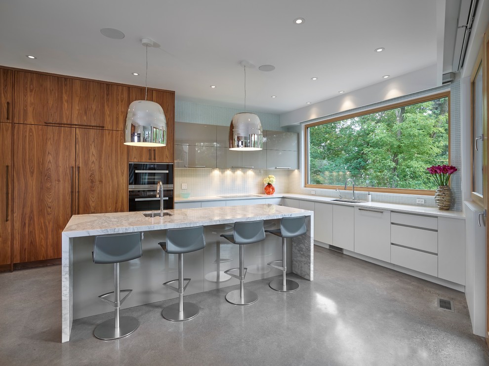 Photo of a large contemporary l-shaped kitchen pantry in Edmonton with a double-bowl sink, flat-panel cabinets, marble benchtops, blue splashback, glass tile splashback, panelled appliances, concrete floors, with island, dark wood cabinets and grey floor.