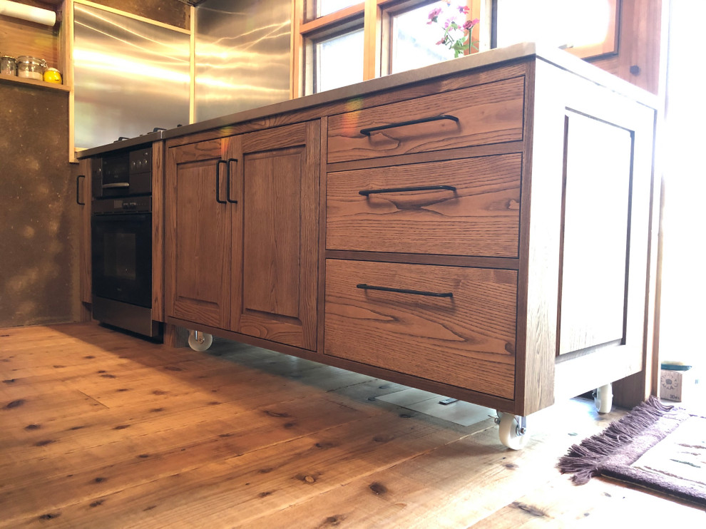 Idéer för att renovera ett orientaliskt kök, med en dubbel diskho, luckor med profilerade fronter, skåp i mellenmörkt trä, bänkskiva i rostfritt stål, stänkskydd i trä, ljust trägolv, en köksö och brunt golv