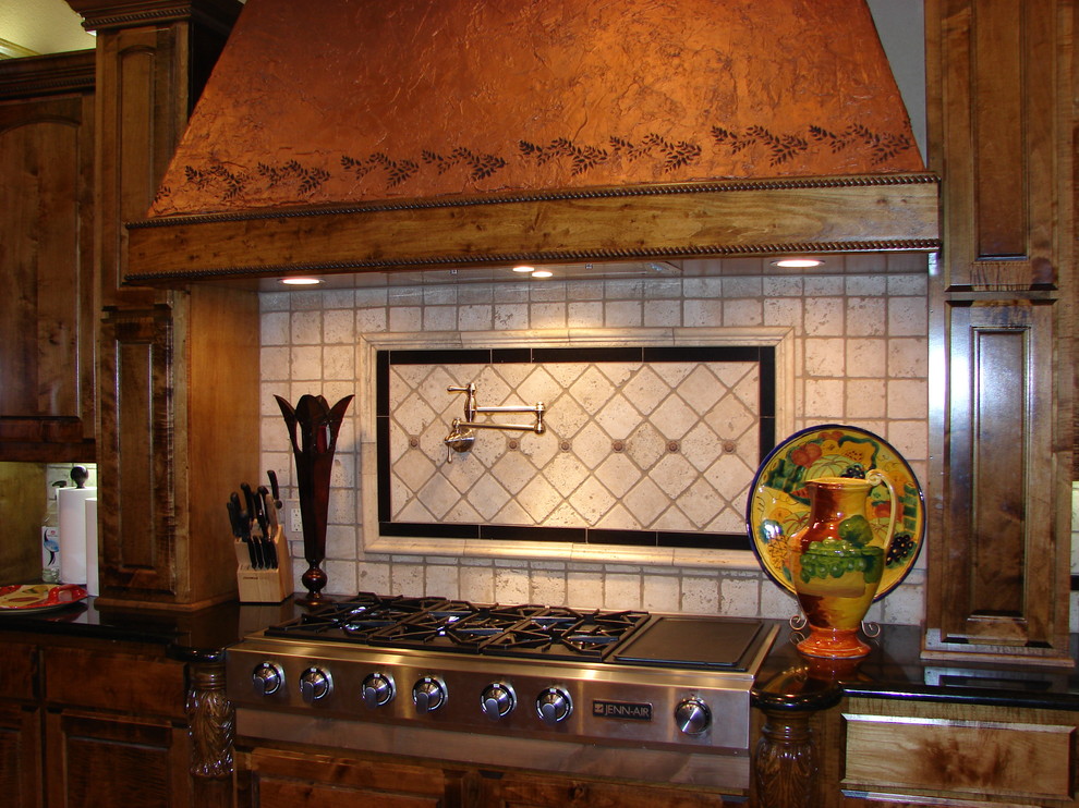 Mediterranean eat-in kitchen in Austin with raised-panel cabinets, medium wood cabinets, solid surface benchtops, stone tile splashback and stainless steel appliances.