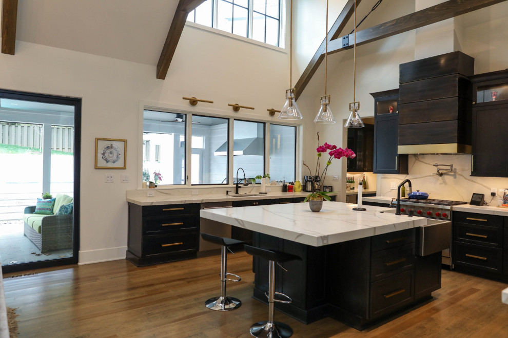 Example of a large transitional u-shaped light wood floor open concept kitchen design with a farmhouse sink, flat-panel cabinets, dark wood cabinets, quartz countertops, white backsplash, quartz backsplash, stainless steel appliances, an island and white countertops
