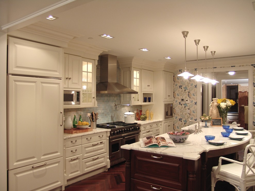 This is an example of a traditional kitchen in New York with raised-panel cabinets, white cabinets, tile benchtops, stainless steel appliances, medium hardwood floors, with island, a farmhouse sink, white splashback and ceramic splashback.