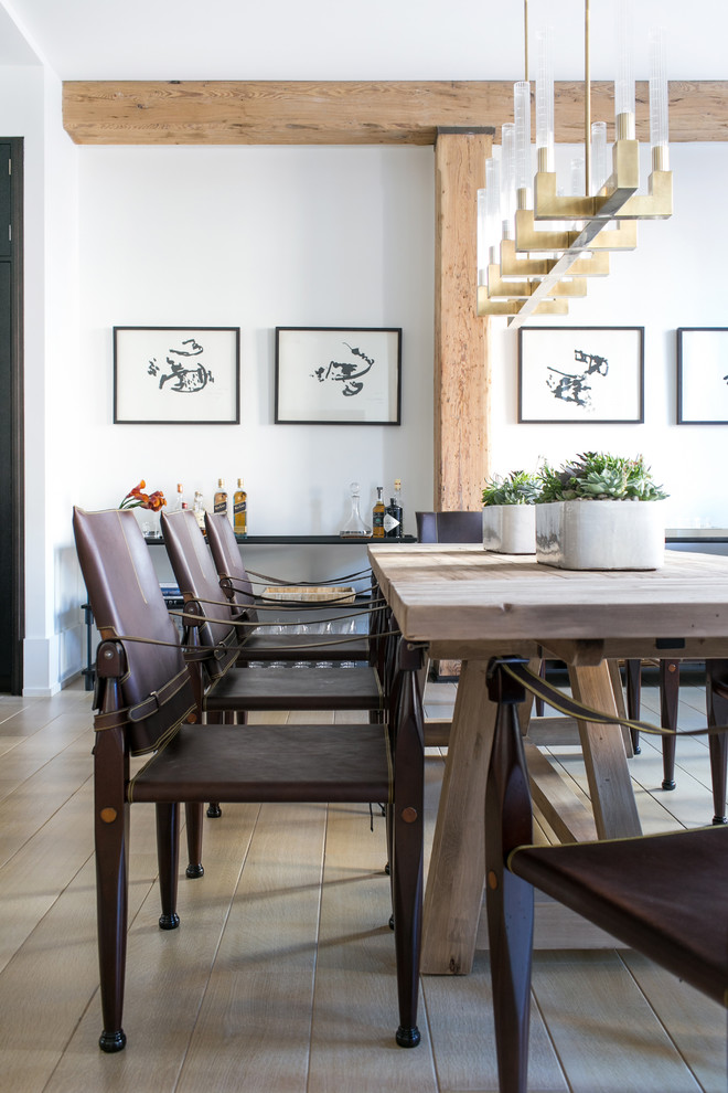 This is an example of a large transitional open plan dining in New York with white walls and light hardwood floors.