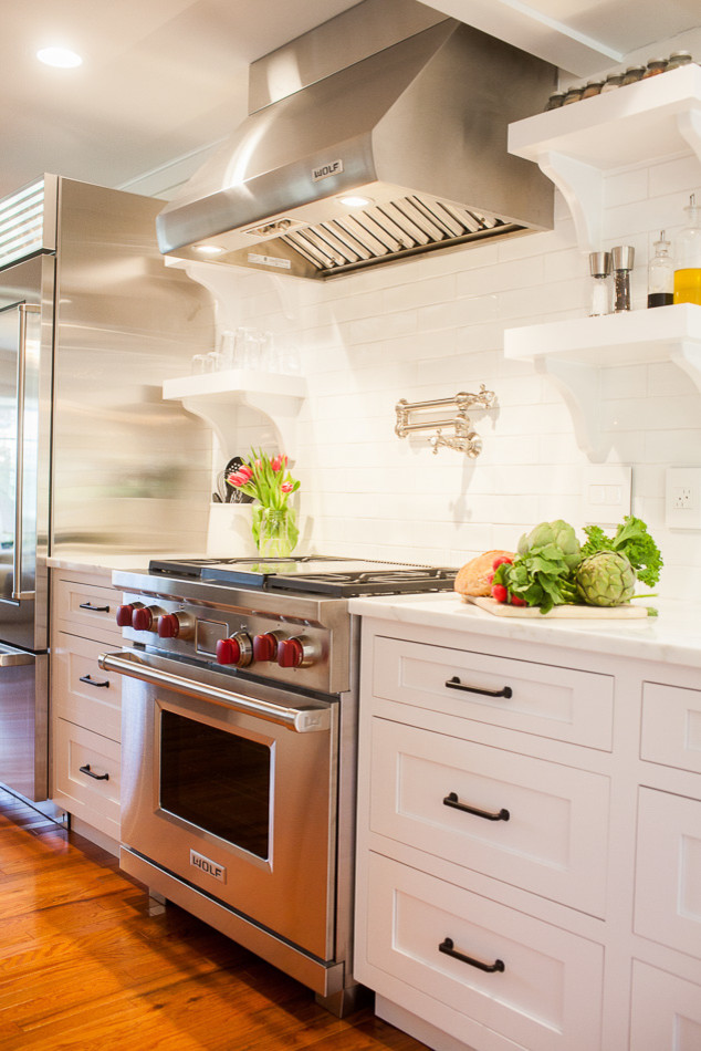 Large transitional medium tone wood floor eat-in kitchen photo in St Louis with a farmhouse sink, flat-panel cabinets, white cabinets, onyx countertops, white backsplash, subway tile backsplash, stainless steel appliances and an island