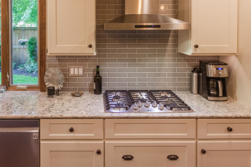 Example of a large transitional single-wall dark wood floor, brown floor and coffered ceiling eat-in kitchen design in Cincinnati with a double-bowl sink, shaker cabinets, white cabinets, granite countertops, gray backsplash, subway tile backsplash, stainless steel appliances, an island and multicolored countertops