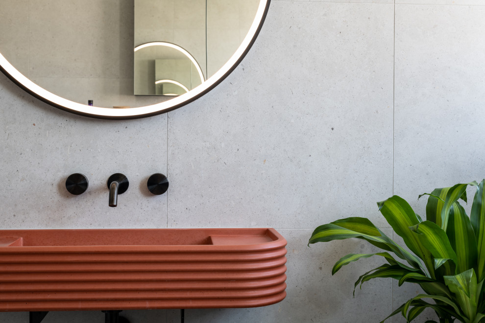 Photo of a mid-sized contemporary kids bathroom in London with a freestanding tub, an open shower, a one-piece toilet, gray tile, porcelain tile, grey walls, porcelain floors, a wall-mount sink, concrete benchtops, grey floor, a hinged shower door, orange benchtops and a single vanity.