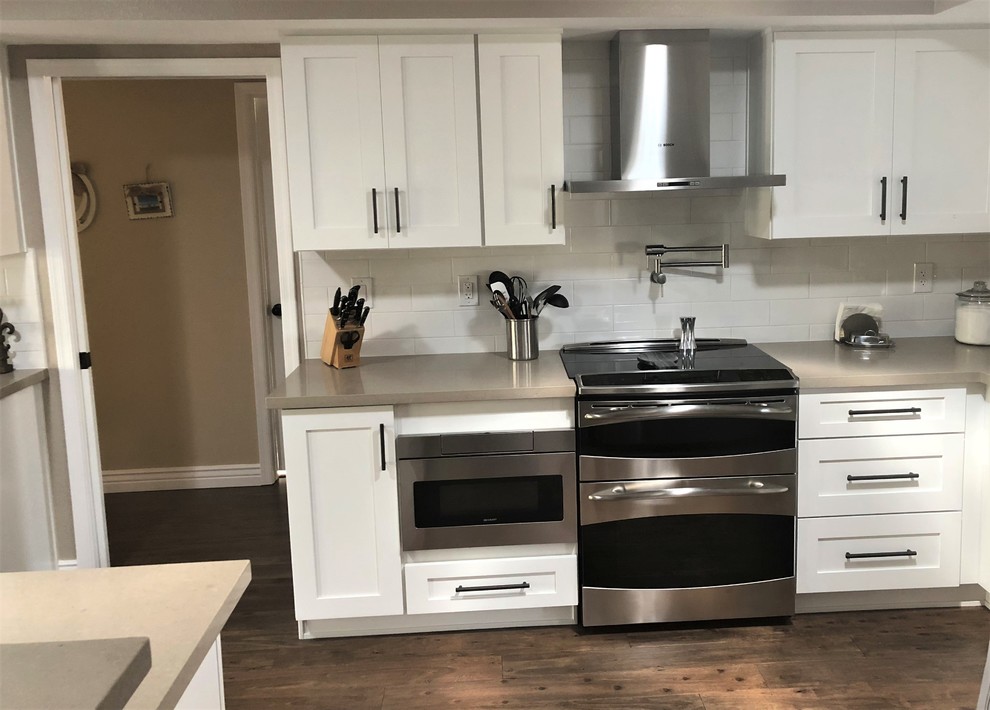 Inspiration for a mid-sized traditional galley eat-in kitchen in Phoenix with an undermount sink, shaker cabinets, white cabinets, quartz benchtops, white splashback, porcelain splashback, stainless steel appliances, dark hardwood floors, with island, brown floor and brown benchtop.