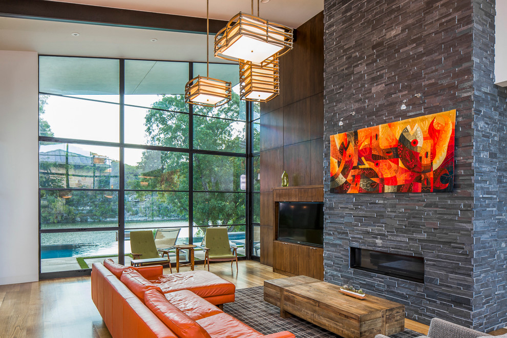 Modern open concept living room in Austin with a built-in media wall, white walls, medium hardwood floors, a ribbon fireplace and a stone fireplace surround.